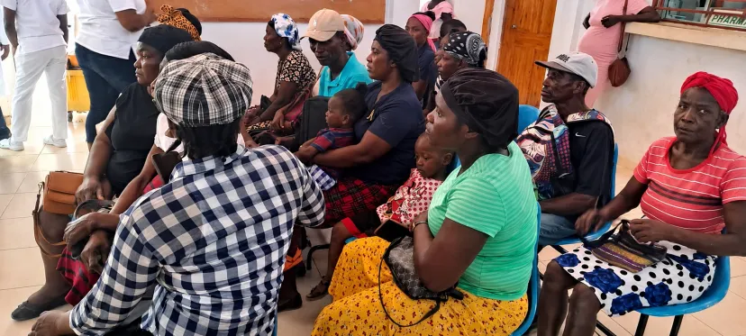 Una sala de espera llena en la clínica, con pacientes y madres con niños pequeños esperando ser atendidos