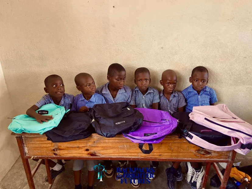 Six students seated at a desk with their new backpacks